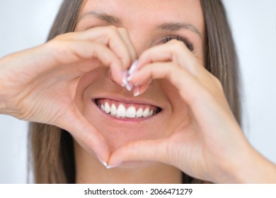 Teeth care. Woman with beautiful smile with strong white teeth. Dental care. Woman holding heart shaped hands near perfect healthy teeth. Stomatology or dentistry concept - Shutterstock ID 2066471279