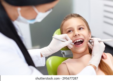 Teeth checkup at dentist's office. Dentist examining girls teeth in the dentists chair