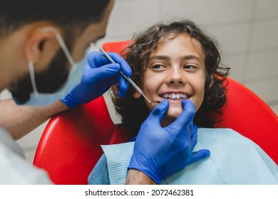 Teeth whitening. Smiling caucasian boy visiting dentist stomatologist orthodontist, curing tooth, putting braces in dental clinic.