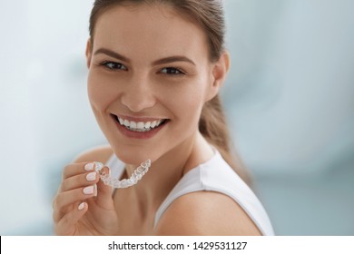 Teeth whitening. Woman with white smile, healthy straight teeth using clear removable braces, invisible teeth tray. Portrait of girl doing dental beauty treatment 