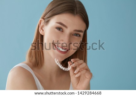 Teeth whitening. Woman with white smile, healthy straight teeth using clear removable braces, invisible teeth tray. Portrait of girl doing dental beauty treatment 