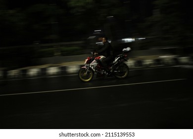 Tegal, Central Java Indonesia - January 30, 2022 : People Riding A Motorcycle Without A Helmet On A Blurred Background At Night 