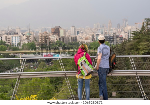Tehran, IRAN - April 9, 2018 Tourists looking\
to Tehran skyline in spring season, modern architectural buildings\
at background. Tabiat bridge\
viewpoint.