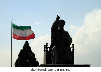 Tehran, Iran - June 10, 2018: A Large Iranian Flag Waving In The Wind Behind A Statue Of Khomeini In Tehran, Iran