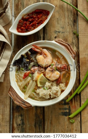 Tekwan or Fish Ball Soup, typical soup dish from South Sumatera. It's homemade fish balls and, rice vermicelli, vegetables in shrimp and fish broth  On wood table, selected focus