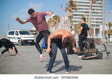Tel Aviv –March 12th 2021: Capoeira group training at the beach promenade. Couples of young Israeli practitioners playing with each other.
