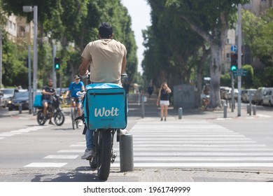 Tel Aviv –April 20th 2021: Food delivery worker, with a ‘Wolt’ thermal bag on the back of his electric bike, waiting to cross an intersection at Rabin square.