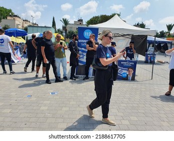 Tel Aviv, Israel - August 10, 2022: Blond Female Voter Checking Up Her Smartphone In Front Of Boaz Bismuth Tent, Some Men And Women. Likud Party Primary Election At Menora Mivtachim Arena.