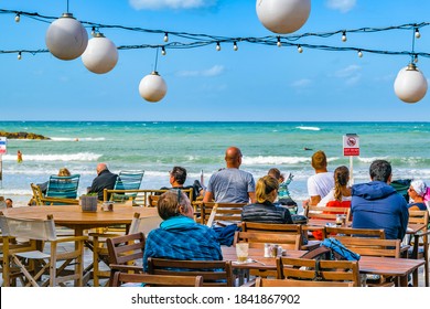 TEL AVIV, ISRAEL, DECEMBER - 2019 - People enjoying a sunny day at promenade waterfront bar, tel aviv, israel