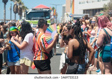 Tel Aviv - June 14th 2019: Pride Parade: Group Of Young People In The Crowd. Truck Pulling A Parade Float In Far Background.