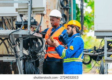 Telecom engineer and technician inspect communication equipment during network maintenance and upgrade operation. Infrastructure inspection, troubleshooting, cable management for reliable connectivity