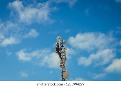 Telecom Worker Repairing 5G Antenna Tower On Blue Sky Background, Cellular Tower System.
