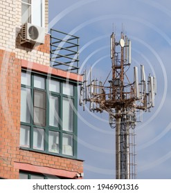 Telecommunication antenna on a tower near a residential multi-storey building. Cellphone antenna in urban area.