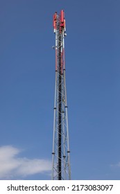 Telecommunication Antenne On A Lattice Tower Painted Red And White In Front Of A Blue Sky. 