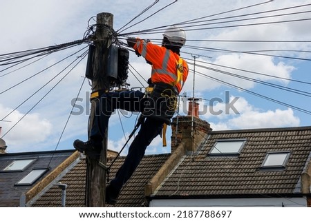 Telecommunication engineer performing maintenance at the top of a telephone pole.