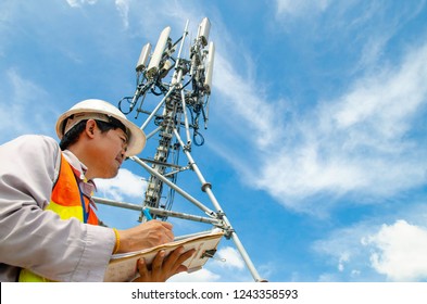 Telecommunication Engineer Writing On Notepad At Tower Site.Technician Record Data Of Maintenance To Checklist.