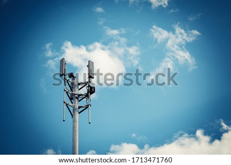 Telecommunication tower with 4G, 5G transmitters. Cellular base station with transmitter antennas on a telecommunication tower on against a blue sky with clouds.