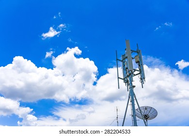 telecommunication tower and satellite dish under cloudy blue sky - Shutterstock ID 282204533