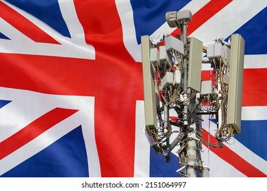 Telecommunications Tower With A 5G Cellular Network Antenna Agains Flag Of UK. Telecommunication Tower Of 5G Cellular Communication. 5G Technology Usage On Telecommunications Towers In United Kingdom