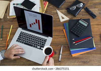 Telecommuting Concept. Man Working On Computer Presentation Sitting At Rough Wood Desk Overhead Top View Keeping Coffee Mug Many Office Supplies Creative Disorder Focus On Plate With Fresh Strawberry