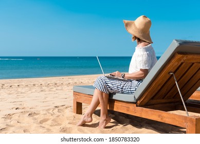 Telecommuting remotely business woman relaxing on the beach using laptop pc computer, education learning, teaching. Sun shining daytime natural blue sky background dream workplace. Back side view. - Shutterstock ID 1850783320