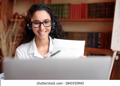 Teleconference And Telecommuting. Portrait Of Smiling Woman In Glasses Having Video Conference On Computer, Showing Paper Document Contract To Camera, Giving Presentation Or Online Class To Students