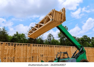 Telehandler maneuvers timber at construction area surrounded by trees on construction site
