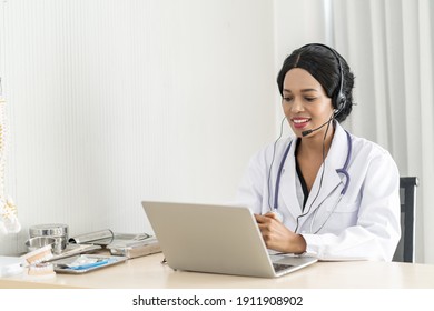 Telehealth, an African woman doctor in headset taking calling on her headset microphone online for a ache patient