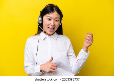 Telemarketer Chinese Woman Working With A Headset Isolated On Yellow Background Making Guitar Gesture