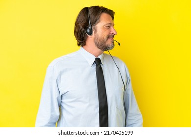 Telemarketer dutch man working with a headset isolated on yellow background looking side