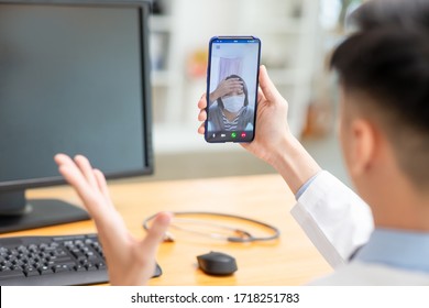 Telemedicine Concept - Asian Female Patient Consult Her Health Condition To Male Doctor By Talking On Mobile Phone And She Feel Headache