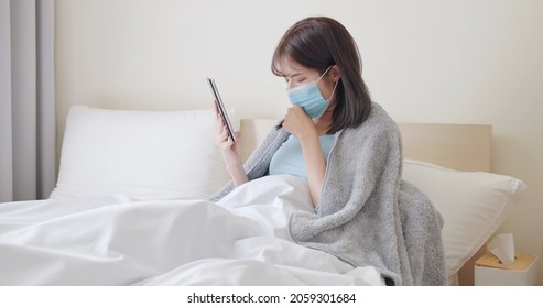 telemedicine concept - asian woman patient wearing face mask is talking about her sick symptom to doctor by digital tablet on bed - Powered by Shutterstock