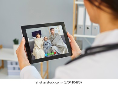 Telemedicine Concept. Family Doctor Online Call. Shoulder View Doctor Therapist Speaks With A Sick Family Video Chat Using A Tablet In A Clinic Office.