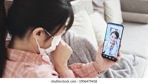 Telemedicine Concept - Rear View Of Asian Woman Has Video Chat With Female Doctor By Smartphone