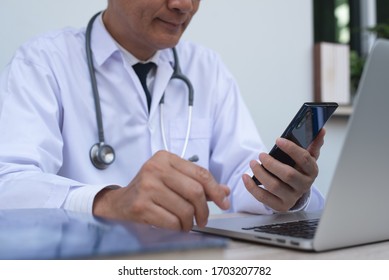 Telemedicine, Teleconference, Medical Research And Technology Concept. Doctor Using Mobile Smart Phone, Working On Laptop Computer In Medical Workspace On Desk In Hospital Office, Close Up