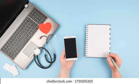 Telemedicine Or Telehealth Virtual Visit, Video Visit, Remote Doctor Video Chat Consultation Concept With Laptop, Doctor Hand, Smartphone, Notepad And Stethoscope On Blue Background.