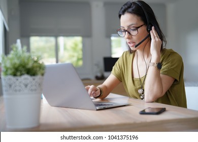 Teleoperator working in office with laptop and headset on