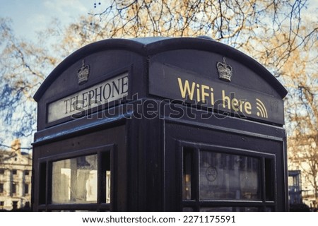 Telephone booth in London symbolises the transition from telephone to voice over ip.
Black phonebooth with wi-fi symbol and telephone symbol.