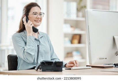 Telephone, Computer And Business Woman In Office, Talking Or Conversation. Landline, Receptionist And Happy Female From Canada In Phone Call, Discussion Or Work Call On Desk In Company Workplace.