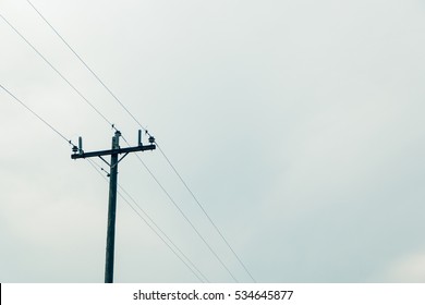 Telephone Electrical Poll Outside. Tall Wooden Telephone Poll With Lots Of Negative Space To The Right. Big Cloud Covered Sky. 