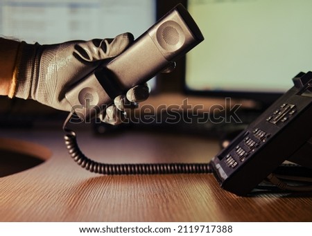Telephone fraud and night theft by a criminal hacker on a phone conversation. A man hand in a black glove with a phone on a dark background