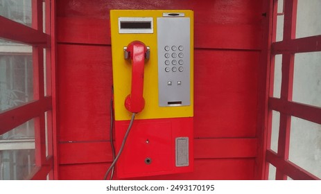 Telephone from an old telephone booth installed in a city with red background - Powered by Shutterstock