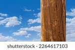 Telephone pole close up with wood grain and a cloudy sky background