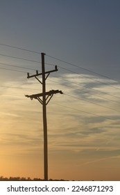 A Telephone pole at Sunset with powerlines for Electricity with clouds that's west of Nickerson Kansas USA out in the country.