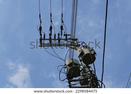 Telephone poles, transformers, and power lines against a blue sky.