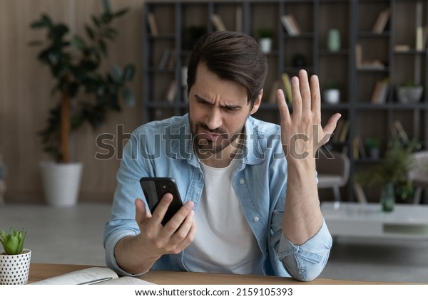 Telephone problem. Upset angry millennial male\
feel outraged by bad wrong work of smartphone app poor weak wifi\
signal. Worried nervous young man missed business phone call get\
too much spam\
messages