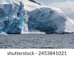 Telephoto of a giant chunk of ice calving off an ice sheet. Graham Passage, near Charlotte Bay, on the Antarctic Peninsula