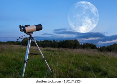 A Telescope On A Tripod Stands In The Field. The Moon Is In The Sky. The Concept Of Amateur Astronomy.