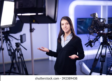 Television Presenter Recording In Television News Studio.Female Journalist Anchor Presenting Business Report.News Camera,light Equipment Behind The Scenes.Talking At Camera To The TV Audience.