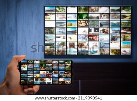 Television streaming, TV broadcast. a man with a phone in his hand and a TV with same image on the screens. cross-platform. Multimedia streaming VoD content provider.